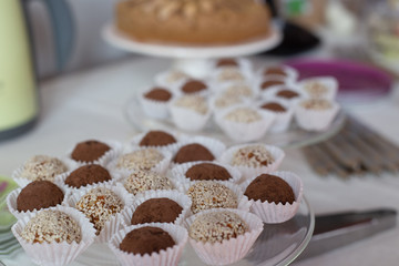 small cakes, sprinkled with ground nuts and cocoa, in paper tins on a glass plate