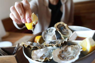 Woman sprinkles oysters with lemon juice in restaurant