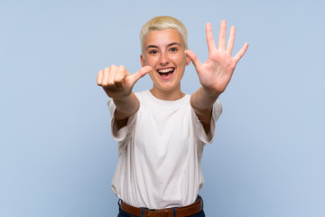 Naklejka premium Teenager girl with white short hair over blue wall counting six with fingers