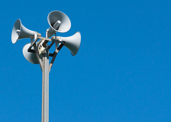 Four loudspeakers attached to a rack on a blue background.