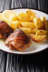 Traditional Greek Lemon Garlic Roasted Potatoes (Patates fournou)  with grilled chicken thighs on a plate close-up. vertical
