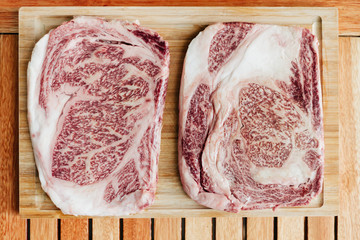 two raw wagyu kobe steaks on a cutting board
