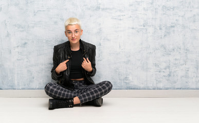 Young woman sitting on the floor with surprise facial expression