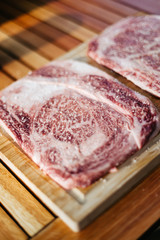 two raw wagyu kobe steaks on a cutting board