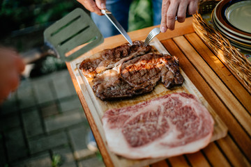 hands of a man cutting slices of grilled kobe beef