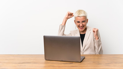 Teenager girl with short hair with a laptop celebrating a victory