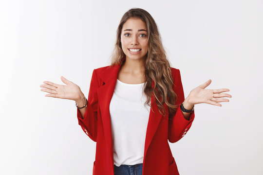 Studio shot clumsy silly cute female trainee apologizing saying oops smiling guilty awkward shrugging, put hands sideways sorry making mistake, explaining herself, standing white background