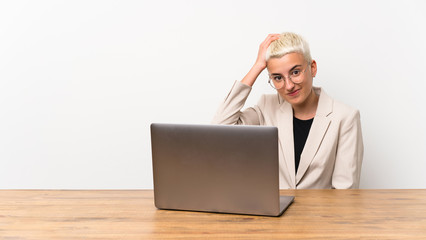 Teenager girl with short hair with a laptop with an expression of frustration and not understanding