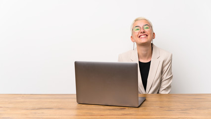 Teenager girl with short hair with a laptop with glasses and happy