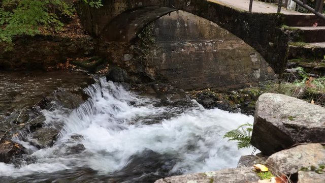 Cozy romantic stone bridge over a quick stream in the mountains, fairy tale like scene