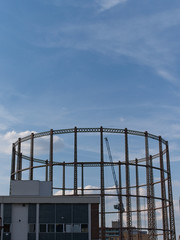 Silhouette of an old gasholder at sunset against blue sky with white clouds in East London, UK.