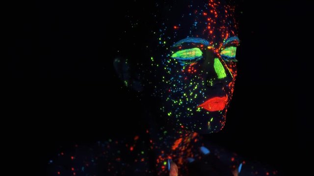 Neon paint on the face. portrait of a girl painted with glowing paint