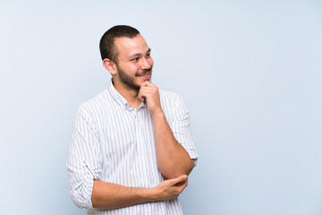 Colombian man over isolated blue wall looking to the side