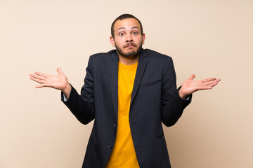 Colombian man over isolated background having doubts with confuse face expression