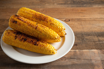 Grilled corn cobs on wood background.
