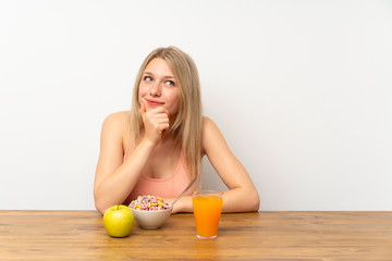 Young blonde woman having breakfast thinking an idea