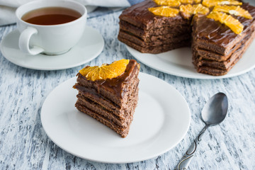 piece of homemade chocolate sponge cake  on white plate cup of tea on white table