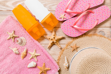 flip flops, straw hat, starfish, sunscreen bottle, body lotion spray on wooden background top view . flat lay summer beach sea accessories background, vaation concept
