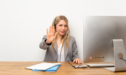 Young woman working with headset making stop gesture with her hand