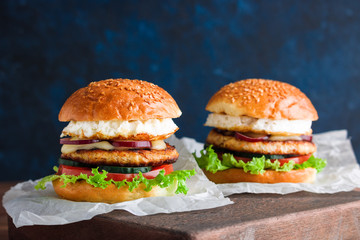 chicken burgers with fried egg cucumber tomato mozzarella cheese lettuce on craft  paper 