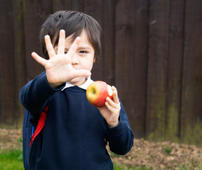 Little boy eating red apples and counting five while waiting shoolbus in the morning, Cute kid carrying school backpack and showing 5 fingers,Back to school, Education or Toddler development concept