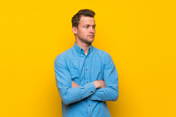 Fototapeta premium Blonde man over isolated yellow wall portrait