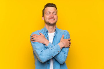 Blonde handsome man over isolated wall hugging