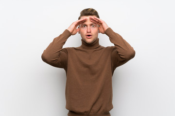 Blonde man over isolated white wall with surprise and shocked facial expression