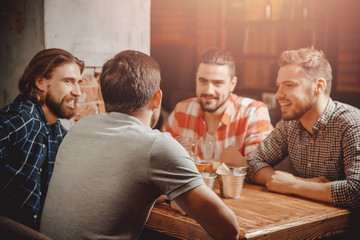 Drinking craft beer from glasses in pub, group of male friends. Concept evening after work meeting...