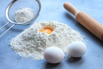 Preparation of dough, flour, eggs and rolling pin on gray background.