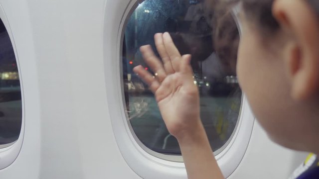 teen girl says goodbye waving his hand at the window lifestyle of the plane aviation aircraft concept. young girl looks out the airplane sitting by the window. flight at night by plane