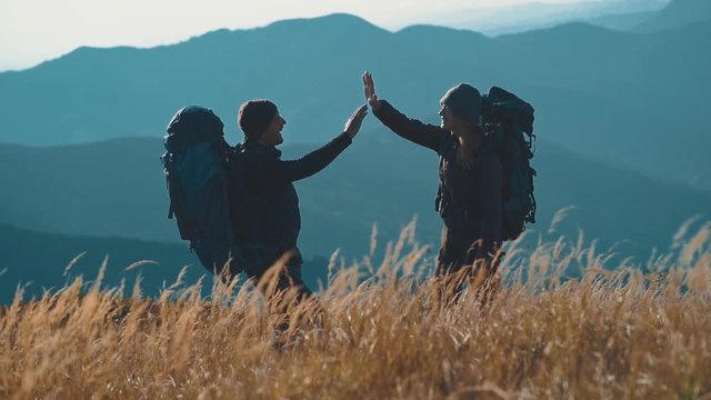 The couple with backpacks greeting on the beautiful mountain. slow motion