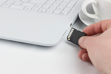 insert sd card in laptop, hand with sd card next to a sd card slot in a laptop