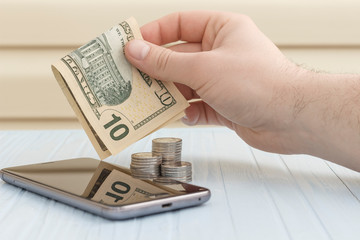 concept, top up on your phone. hand with banknote over mobile phone