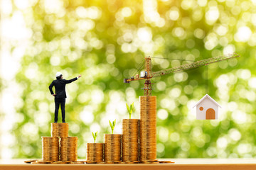 Man engineers in hard hat helmet is working on stack gold coin with grow value and tower crane with...