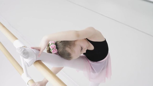 Top view of little girls using ballet barre when doing leg stretching exercises in dance studio