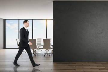 Fototapeta premium Businessman in office with black wall