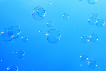 Many large soap bubbles flying in blue sky, city magic