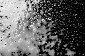 Spilled milk puddle with droplets isolated on black background and texture, top view