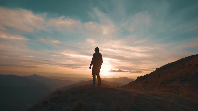 The man standing on the mountain against the beautiful sunset