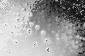 Spilled milk puddle with droplets isolated on black background and texture, top view