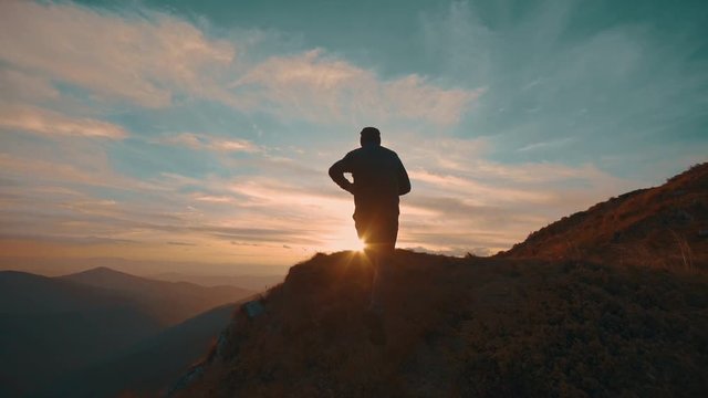 The man jumping on the mountain against the beautiful sunset. slow motion