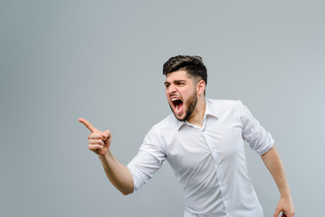 Young man screaming isolated over grey background
