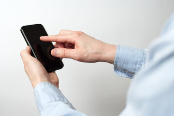 Hand holding and Touch on Black Smartphone with blank screen on gray background
