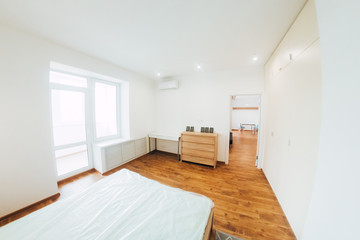 modern light interior. bedroom with white walls and ceiling. wooden bed and two white bedside tables.