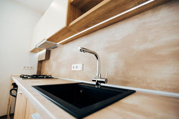 modern kitchen with neon lighting. chromed faucet and black square sink.