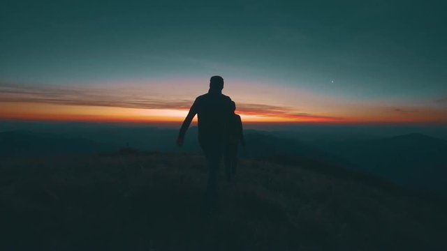 The man and woman walking along the evening mountain. slow motion