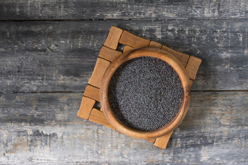 Pastry poppy seeds in a wooden bowl on a grey wooden table