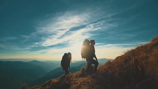 The couple with camping backpacks walking to the mountain top. slow motion