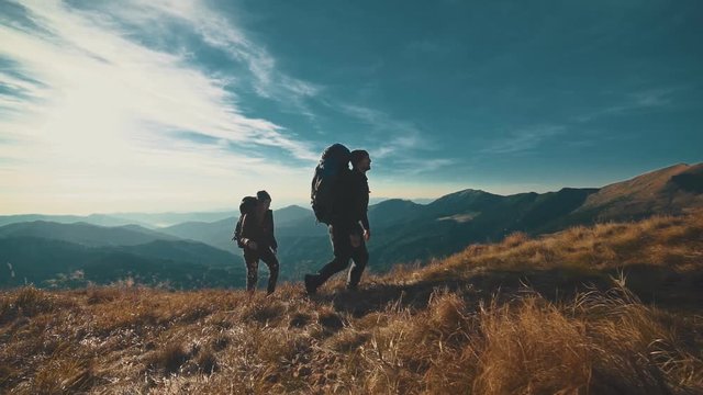 The couple walking on the mountain on a sunny background. slow motion